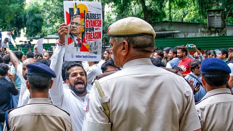 ایک شخص پولیس افسران کے سامنے "گیانیش کو غداری کے الزام میں گرفتار کرو" کا پلے کارڈ اٹھائے ہوئے ہے۔